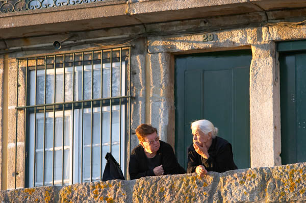 Två gamla damer konverserar i solnedgången i Porto