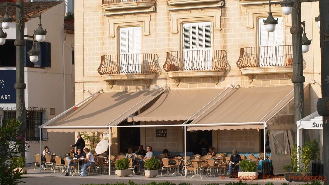 En caféterrass med ett vackert hus i solen i Sitges, Katalonien